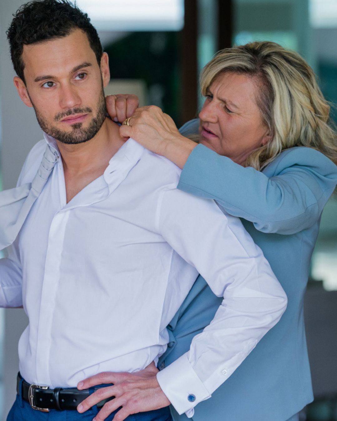 La madre dello sposo lo aiuta a sistemare la camicia durante i preparativi del matrimonio