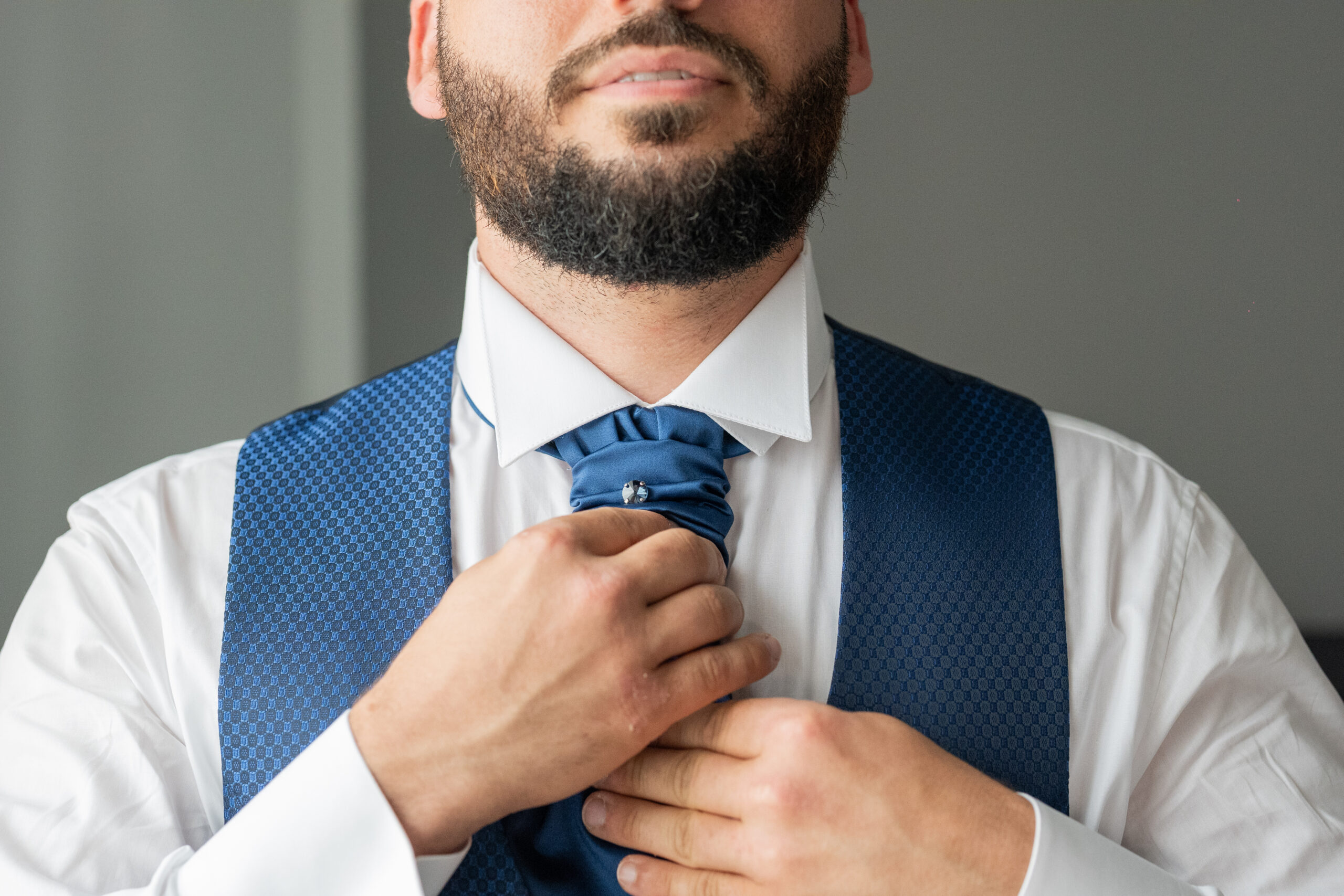 dettaglio sposo che sistema la cravatta blu elegante