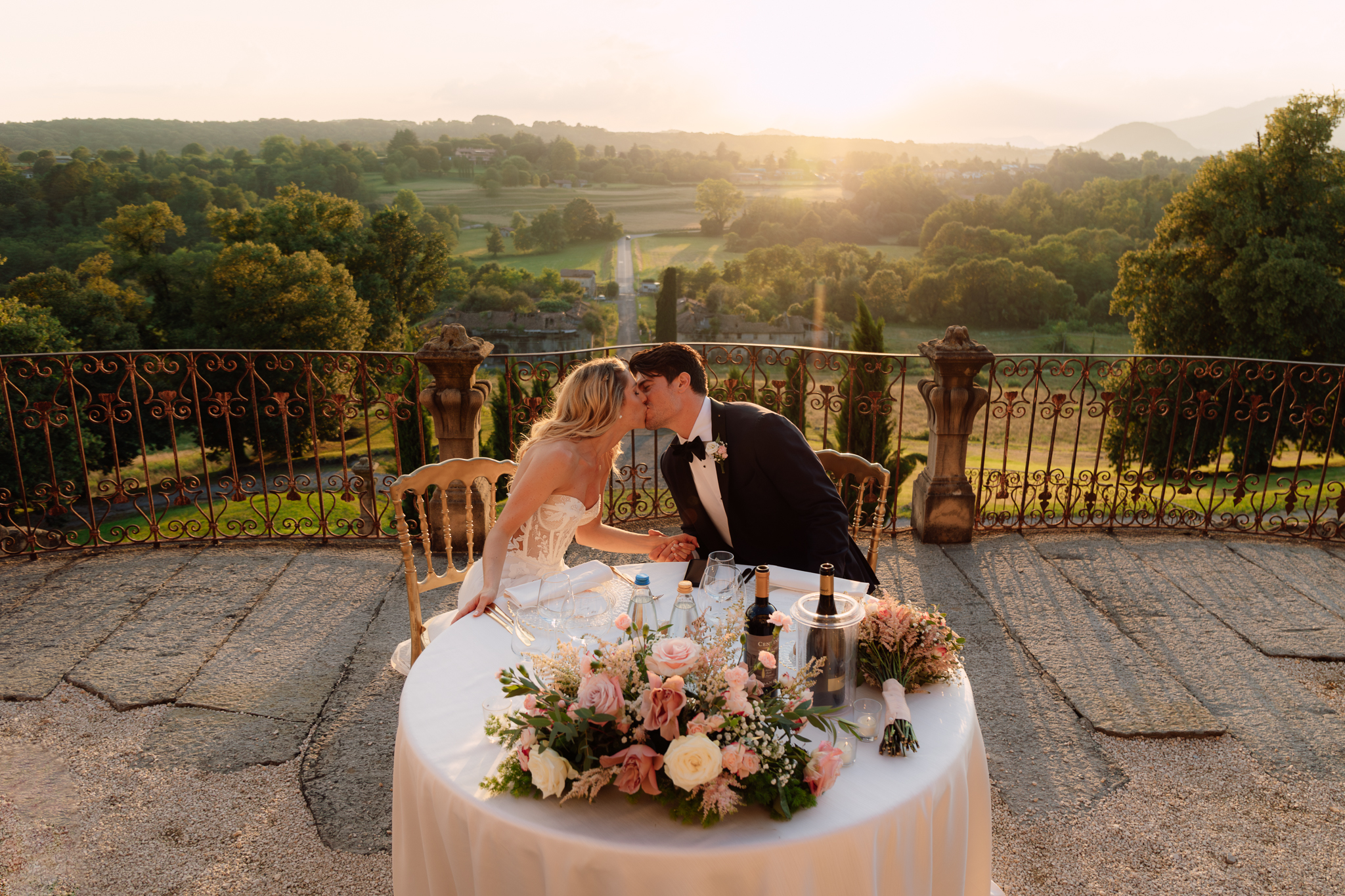 Gli sposi si baciano al tavolo del ricevimento con vista panoramica.