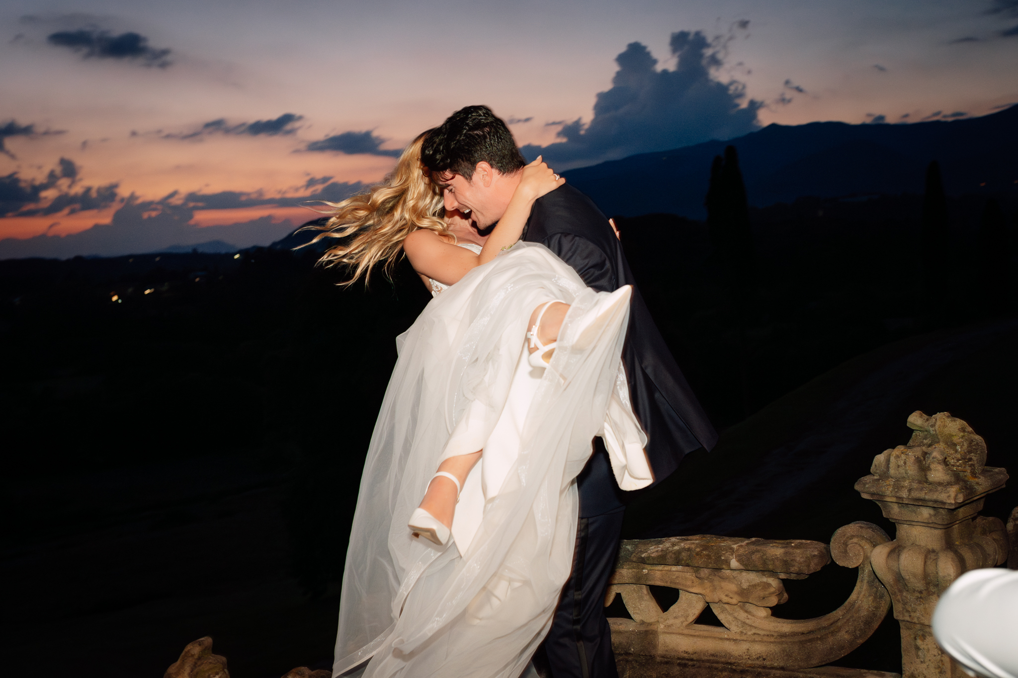 Sposo solleva la sposa tra le braccia durante la sera.