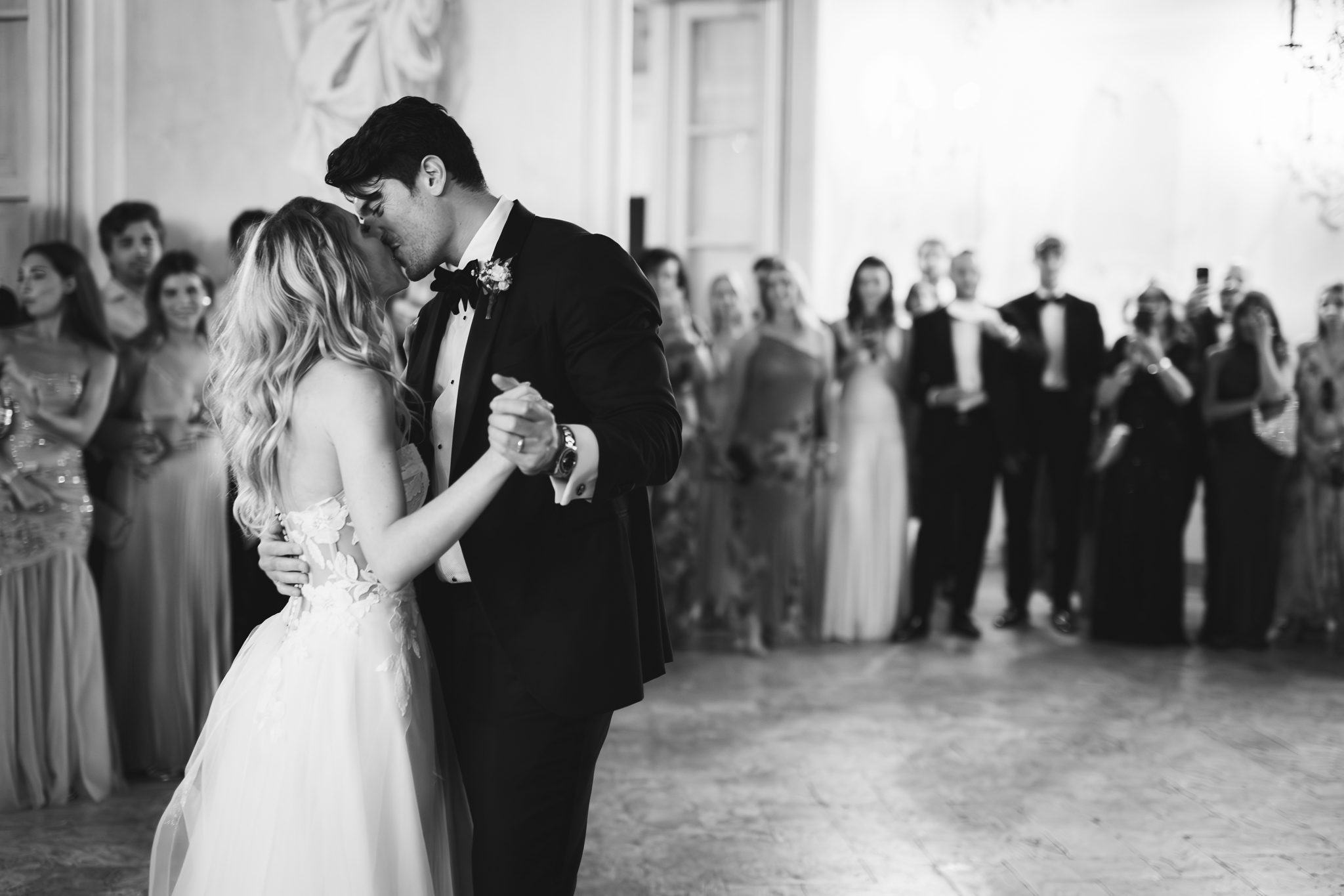 Primo ballo degli sposi in bianco e nero, circondati dagli invitati.