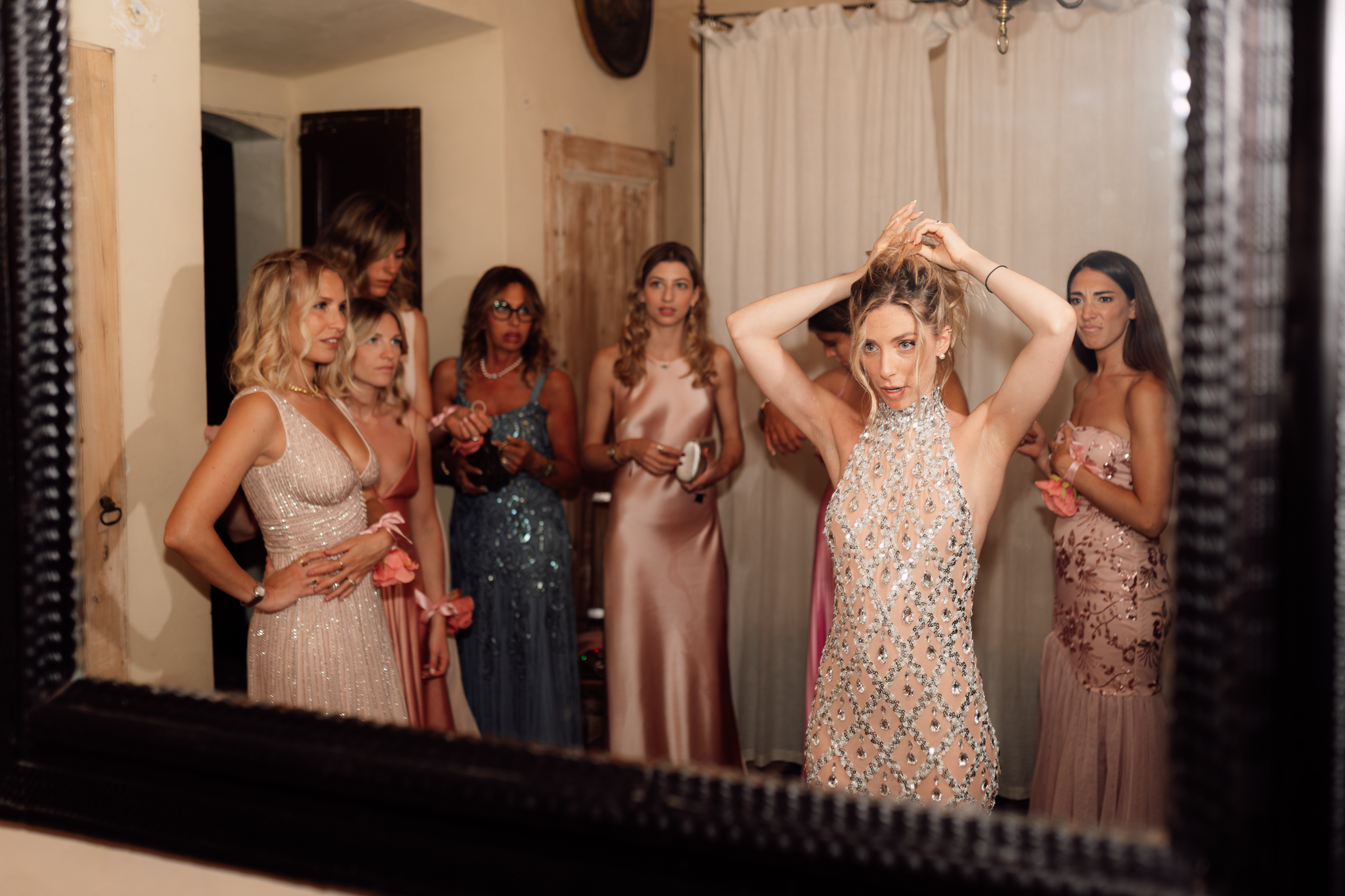 La sposa si prepara al cambio d’abito con le amiche, davanti allo specchio.