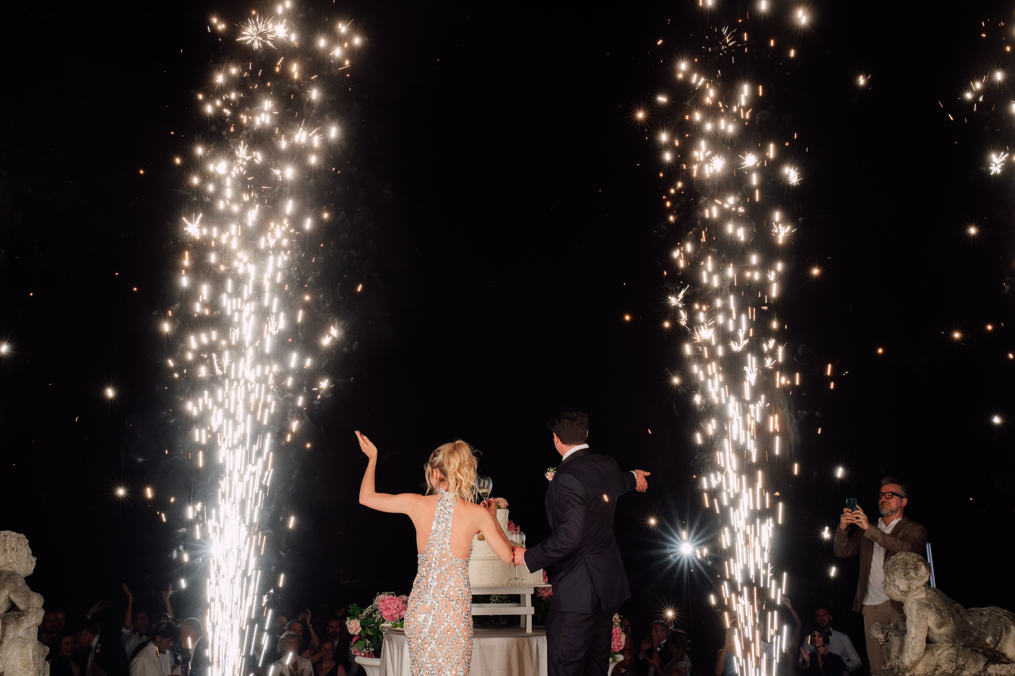Brindisi degli sposi durante il taglio della torta con fuochi d’artificio