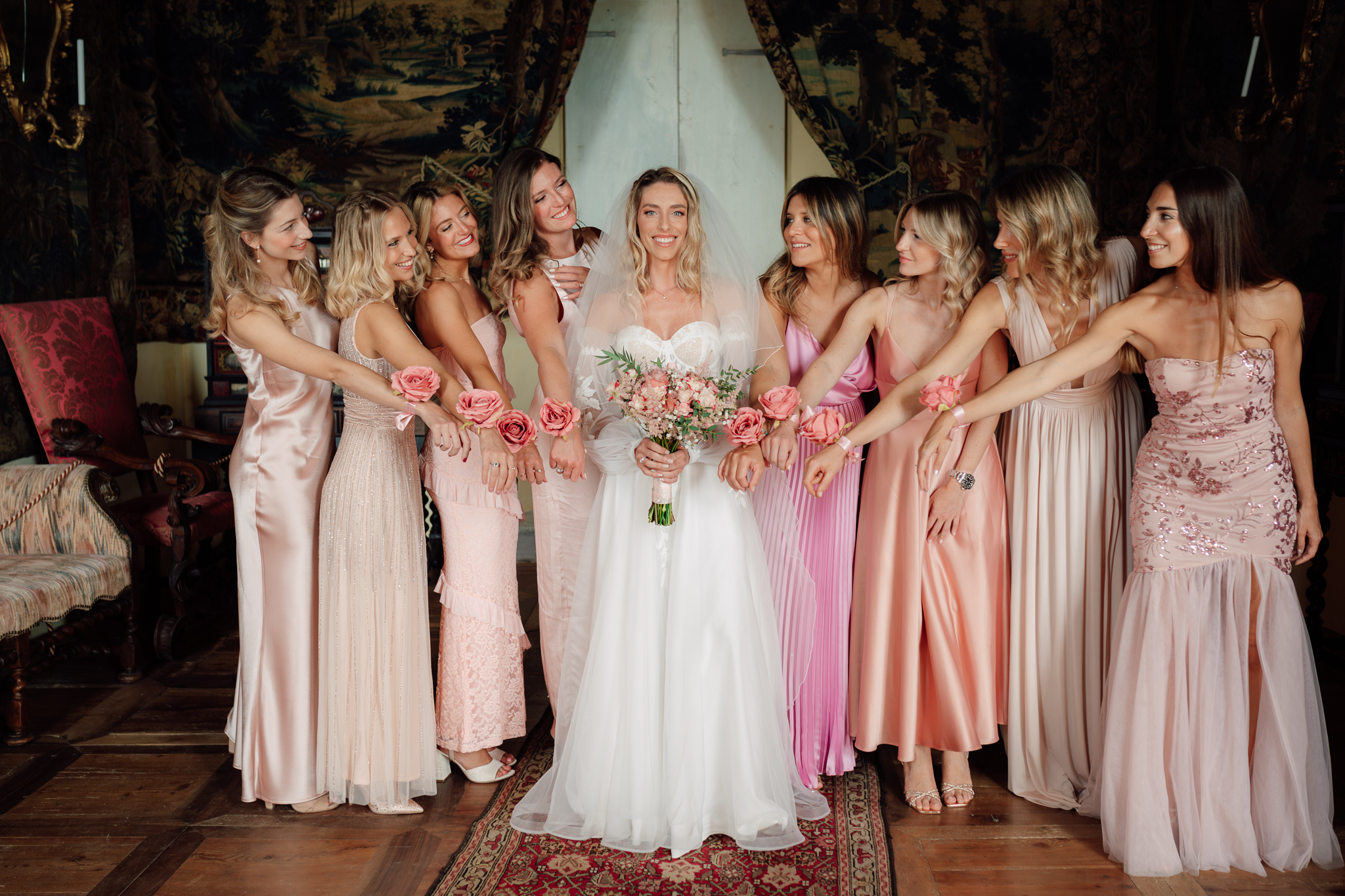 La sposa con le damigelle mostra il bouquet, simbolo di unione e amicizia nel giorno del matrimonio.